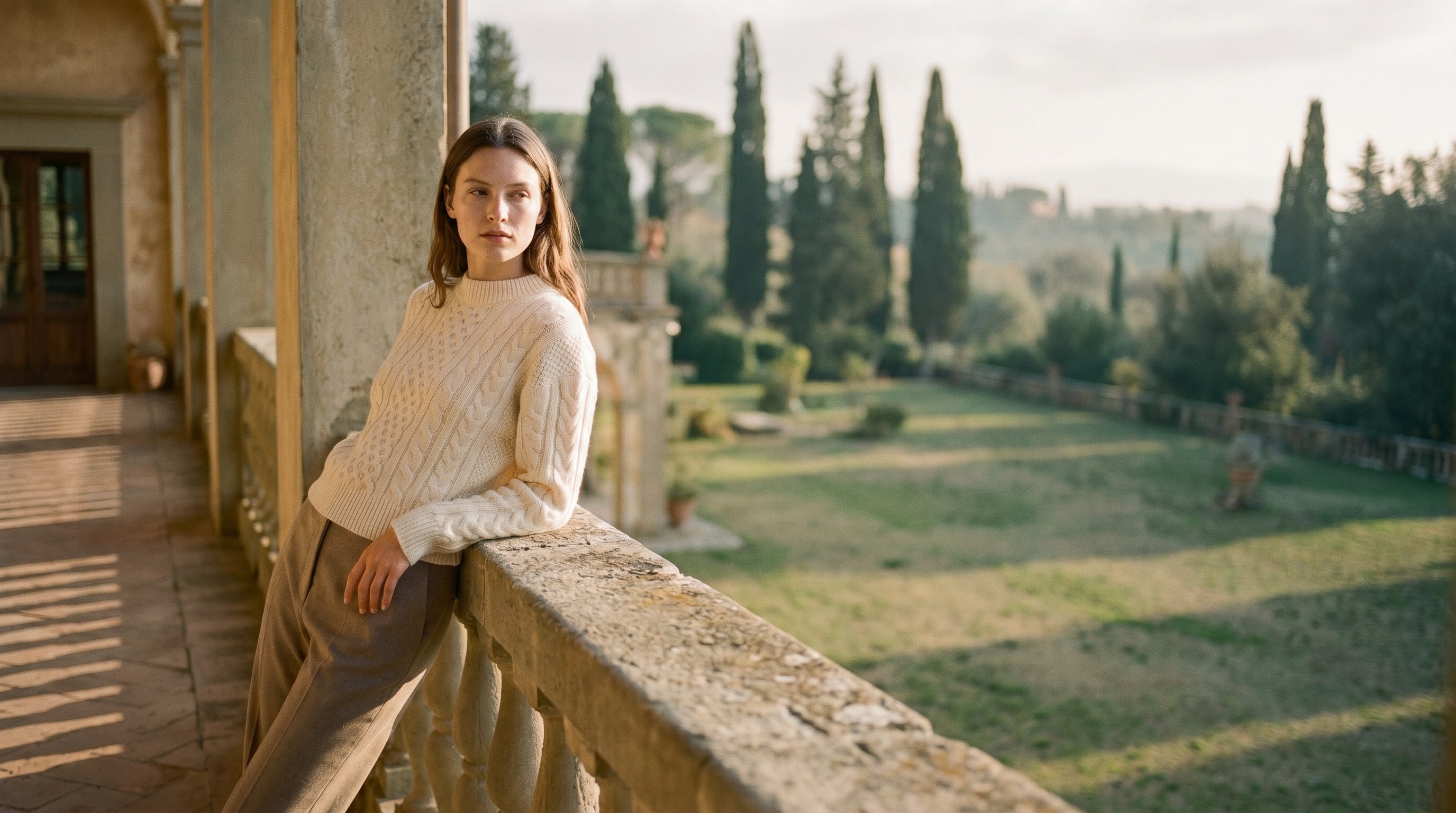 A woman in a cream cable-knit on a sunlit Tuscan villa terrace