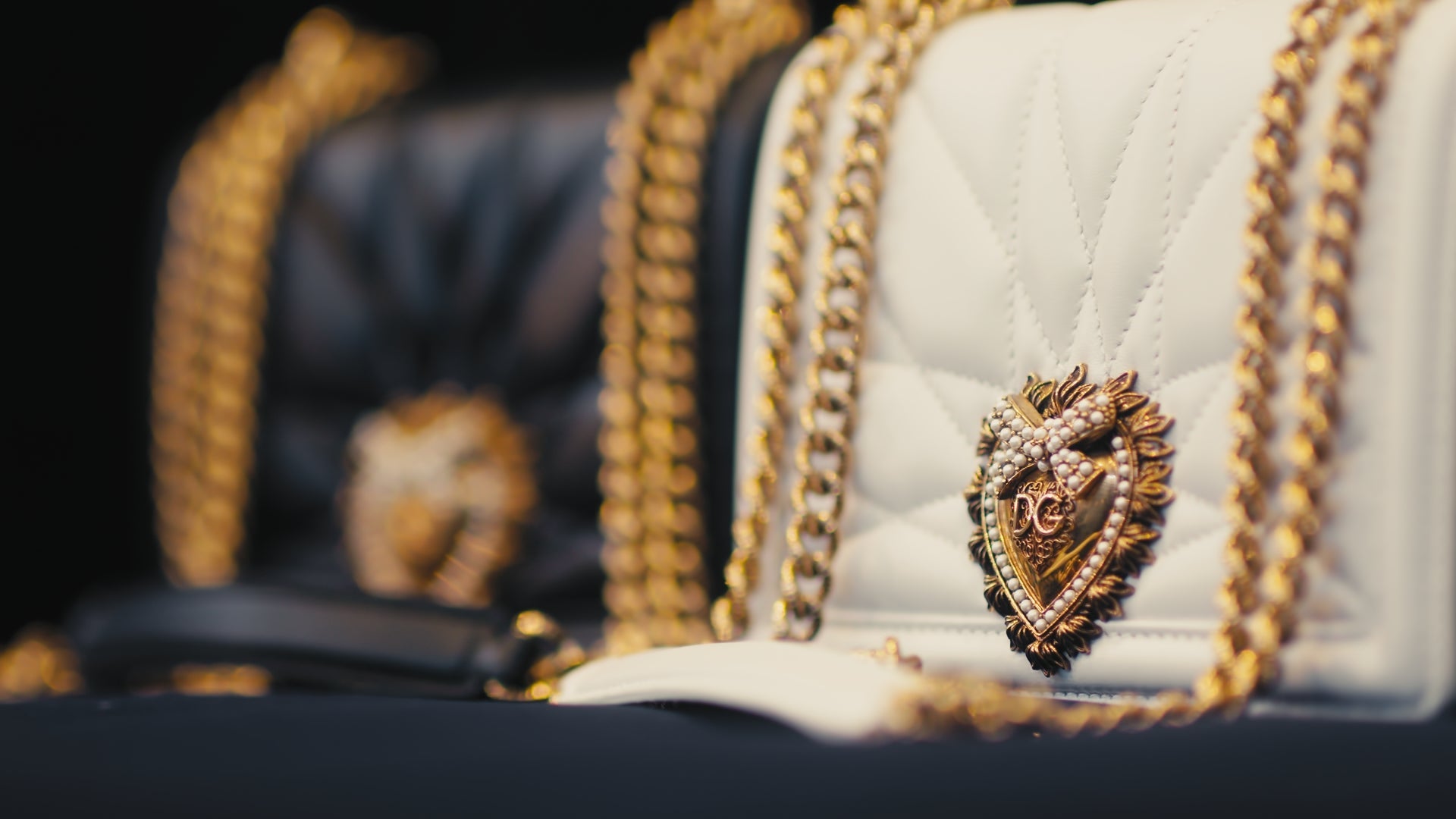 A white quilted Dolce & Gabbana Devotion bag with a gold sacred-heart emblem and chain strap, in warm low light